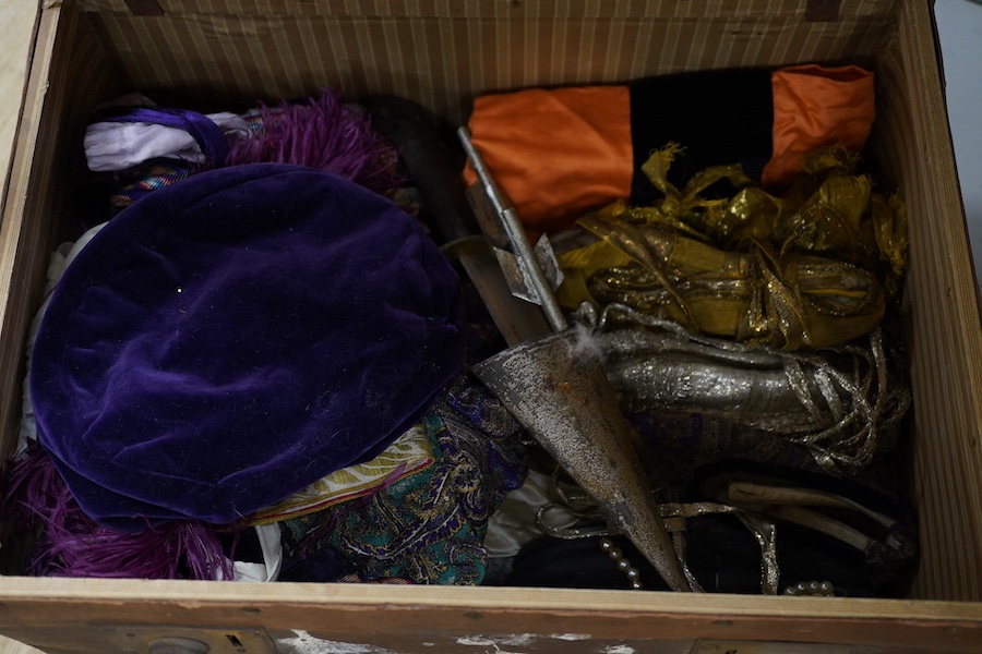 Two trunks containing a collection of children’s fancy dress from early 20th century, including an unusual child’s ‘pearly king’ suit, two earlier stockinette hats, a length of long silver metal fringing, ribboning etc.,
